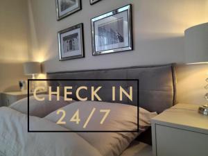 a bedroom with a bed with the check in sign on it at Beige MOOD City Apartment in Wrocław