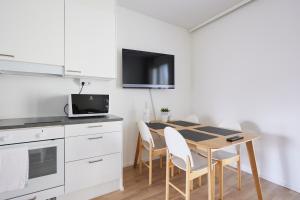 Una cocina con mesa y sillas y un televisor. en Keskeisen sijainnin uudiskohde, Seamless check-in, Baby crib, en Turku