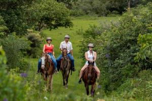 tre persone a cavallo su un campo di Rinconcito Lodge a Hacienda Santa María