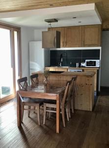 a kitchen with a wooden table and chairs and a kitchen with a counter at Le Flocon - 6 personnes in Saint-Chaffrey