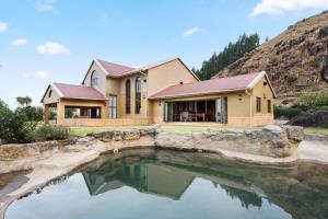 a house with a pond in front of it at Drakensberg Luxury Accommodation - Misty Ridge in Himeville