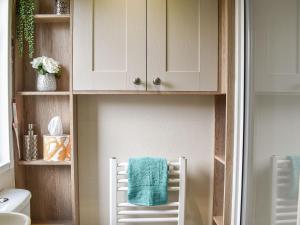 a bathroom with a white chair with a towel on it at Deer Glade Lodge in Landford