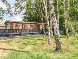 a house with a deck in the middle of a yard at Deer Glade Lodge in Landford