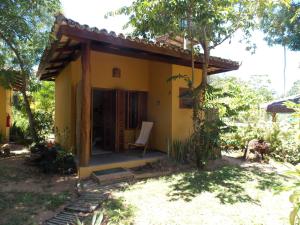 una pequeña casa amarilla con una silla delante en Pousada Ponta do Muta en Barra Grande