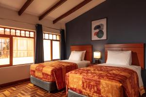 two beds in a room with two windows at Hotel Ankara Boutique in Cusco