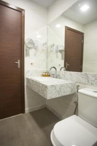 a bathroom with two sinks and a toilet and a mirror at Real Palace Hotel in Rio de Janeiro