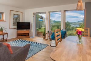 uma sala de estar com uma mesa e cadeiras e uma televisão em Cuillrigh - Luxury house, loch & mountain views em Portree
