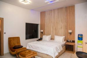 a bedroom with a bed and a chair and a television at Alder studio Apt+Gym+Snooker board. Rhodabode Nile in Abuja