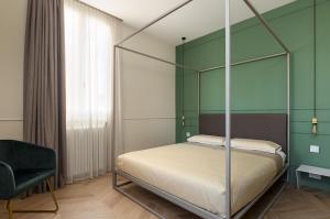 a bedroom with a canopy bed and a chair at Casa Duomo Luxury Suites in Monza