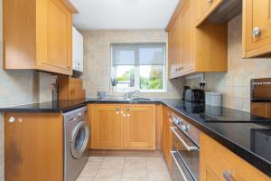 a kitchen with wooden cabinets and a washing machine at Charles Alexander Short Stay - Moorway House in Poulton le Fylde
