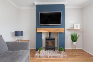 sala de estar con chimenea y TV en la pared en Charles Alexander Short Stay - Moorway House, en Poulton le Fylde