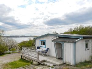 un pequeño cobertizo blanco con una silla en la cubierta en 7 person holiday home in LYSEKIL, en Lysekil