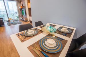 a dining room table with plates and utensils on it at Sunny Vinhome Metropolis Apartment in Hanoi