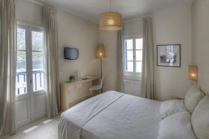 a bedroom with a bed and a desk and windows at Delfini in Kamares