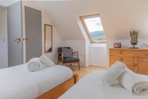 1 dormitorio con 2 camas, silla y ventana en Cuillrigh - Luxury house, loch & mountain views en Portree