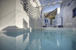 a swimming pool in a white building with water at Delfini in Kamares