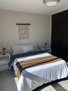 a bedroom with a large bed with a striped blanket at Departamento céntrico, pileta cochera moderno y lujoso in Villa Carlos Paz