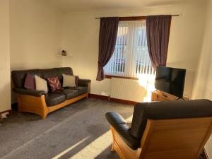 a living room with a couch and a television at Lomond View Apartment in Ladybank