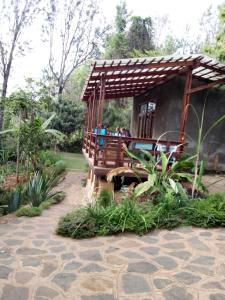 un petit bâtiment avec une terrasse dans un jardin dans l'établissement Lushoto Pazuri, à Makungulu