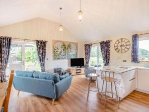 a living room with a blue couch and a kitchen at Violet Cottage in Credenhill