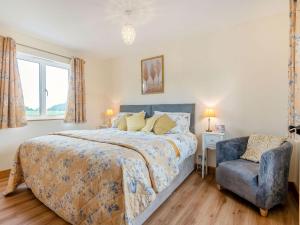 a bedroom with a bed and a blue chair at Violet Cottage in Credenhill