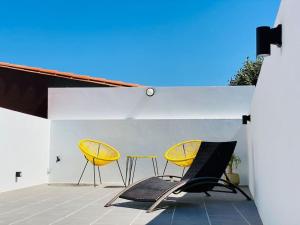 dwa żółte krzesła i stół na patio w obiekcie ÁTICO DALAI - Jacuzzi & Terraza junto al mar y playas w mieście Villanueva de Arosa