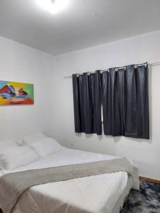 a bedroom with a bed and a window with black curtains at Triunfo Flat in Triunfo