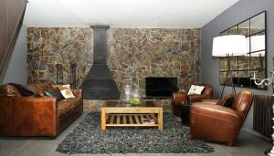 a living room with leather furniture and a fireplace at La Caseta de Queixans con chimenea in Puigcerdà