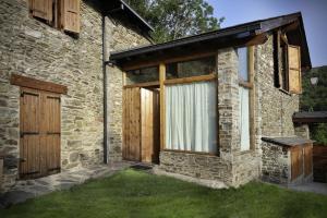 a stone house with a wooden door and a window at La Caseta de Queixans con chimenea in Puigcerdà