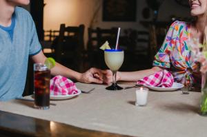 dos personas sentadas en una mesa con una bebida en Hotel Del Rio, en Navojoa