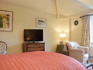 a bedroom with a bed and a flat screen tv at Stable Cottage in Much Birch