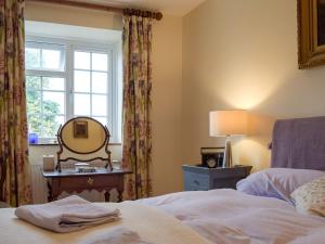 a bedroom with a bed and a mirror and a window at Stable Cottage in Much Birch