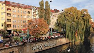 a group of people sitting on a wall next to a river at Arbio I Apartmently Studios & Apartments in Berlin