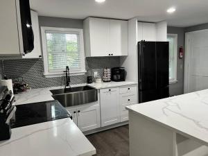 a kitchen with white cabinets and a black refrigerator at Casa Rosado @ Pocono II by Lake Hot Tub Camelback in Tobyhanna +27 photos