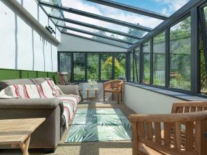 a conservatory with a couch and tables and windows at Four Chimneys in Bratton Clovelly