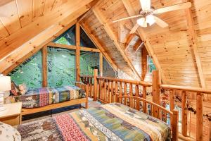 a log cabin bedroom with two beds and a ceiling fan at Bear Pleasures in Gatlinburg