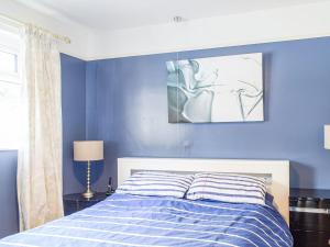 a blue bedroom with a bed and a painting on the wall at Rhiw Gam in Abbey-Cwmhir