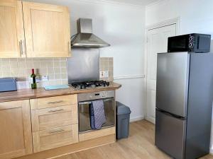 a kitchen with a stainless steel refrigerator and wooden cabinets at Wor Hoose in Amble