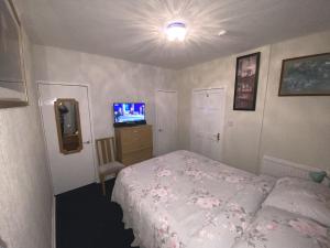 a small bedroom with a bed and a television at Private Lounge and Double Room in Kilwinning