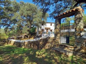a stone house with a gate and a stone wall at La Encina Casa Rural in El Quejigo