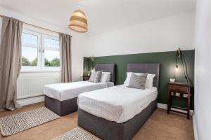 two beds in a room with green walls and windows at Turnberry accommodation in Turnberry