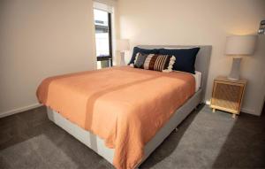 um quarto com uma cama com um cobertor laranja e uma janela em Loch Ard Place em Peterborough