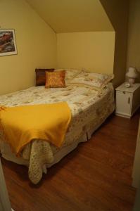 a bedroom with a bed with a yellow blanket on it at Maison d'Imelda in Petit-Saguenay