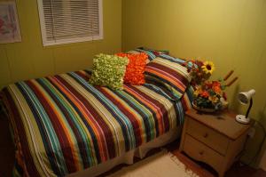 a bedroom with a bed with colorful sheets and flowers on it at Maison d'Imelda in Petit-Saguenay