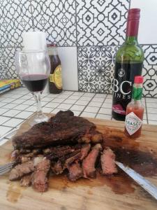 a piece of meat on a cutting board with a glass of wine at Achab Self Catering Tent in Usakos