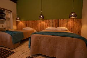 two beds in a bedroom with green walls and lights at Pousada Pitauá in Socorro
