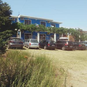 a blue house with cars parked in front of it at Apartments Kraja in Velipojë