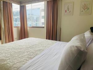 a bedroom with a white bed with a window at Spacious apartment in Miraflores in Lima