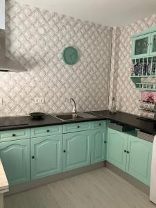 a kitchen with green cabinets and a clock on the wall at CASA AYARAN in Baeza