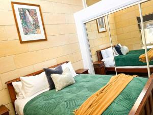 a bedroom with a green bed and a mirror at Bayview no 2 in Port Campbell